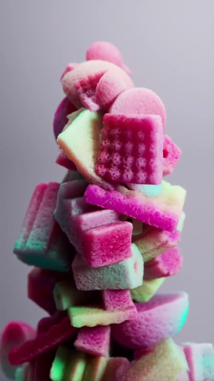 a pile of colorful marshmallows sitting on top of each other in front of a gray background