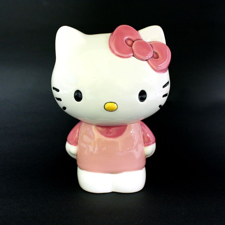 a hello kitty figurine sitting on top of a black surface with a pink bow