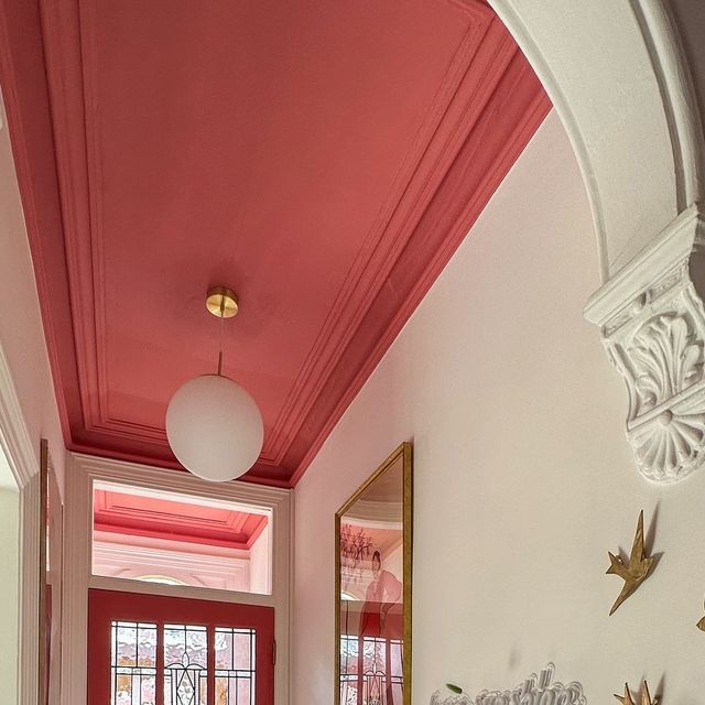 the hallway is decorated in pink and white with gold accents on the ceiling, along with an arched doorway that leads to another room