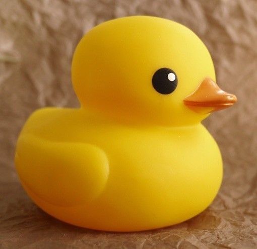 a yellow rubber ducky sitting on top of a brown paper covered surface with black eyes