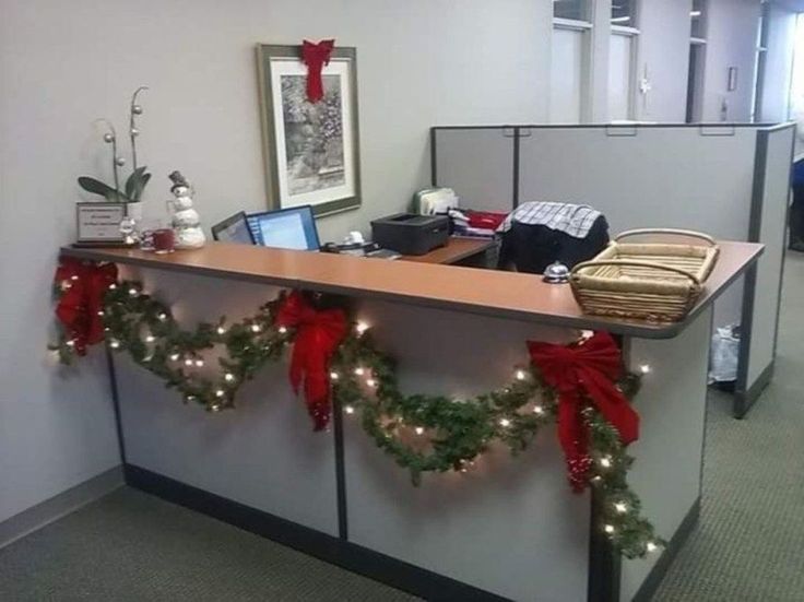 an office cubicle decorated for christmas with garland and lights on the front desk area