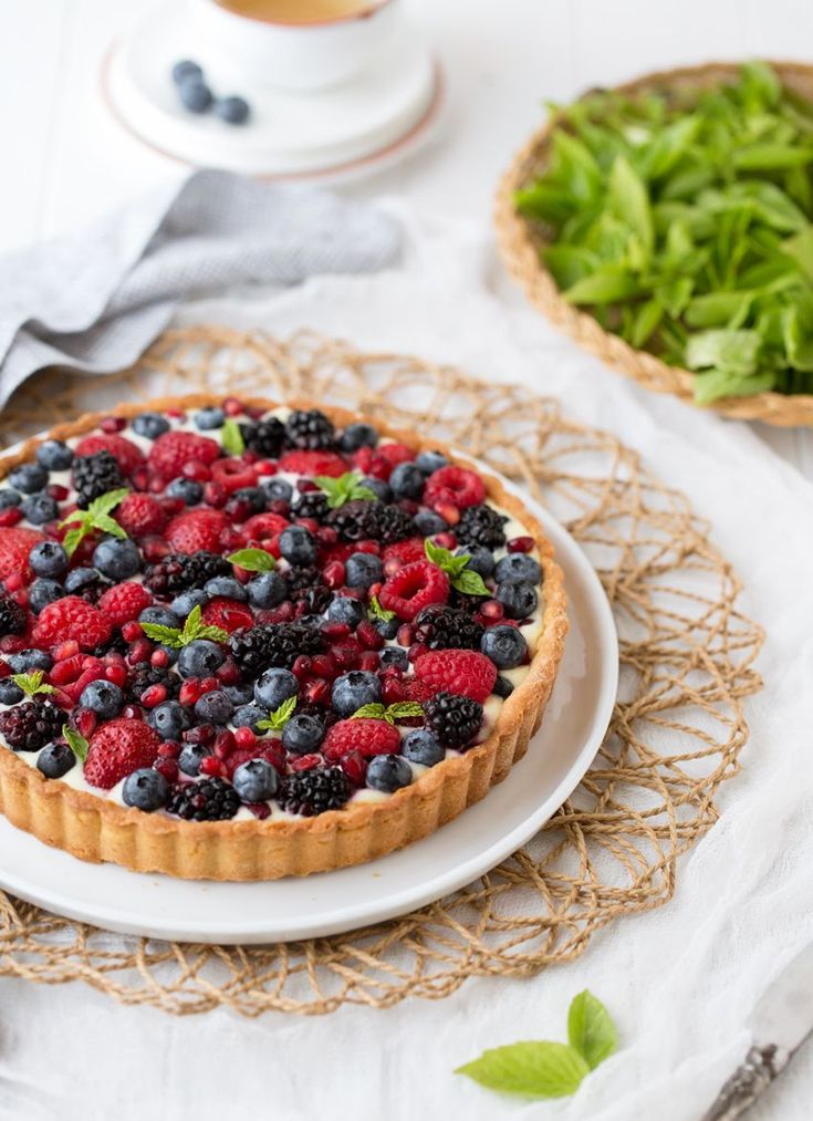 a pie with berries and blueberries on it sitting on a table next to other food