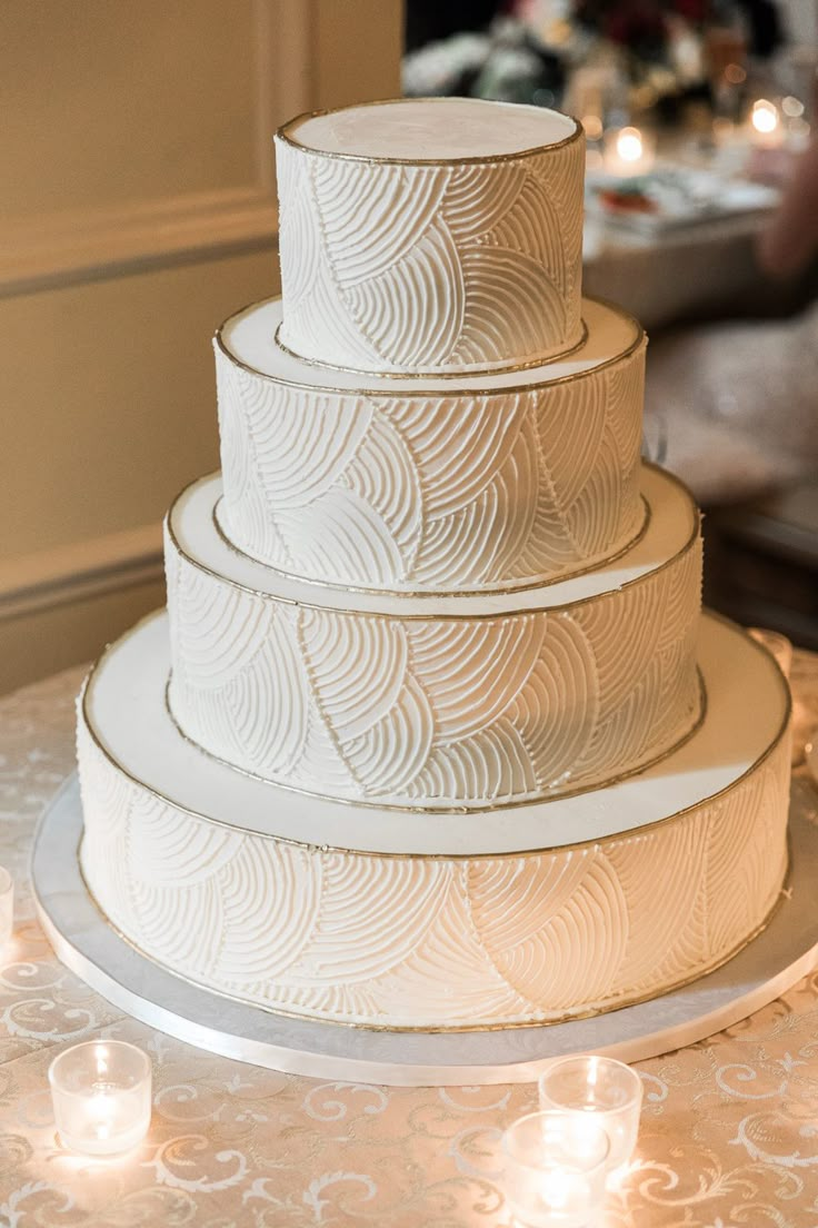 a three tiered white cake sitting on top of a table next to lit candles