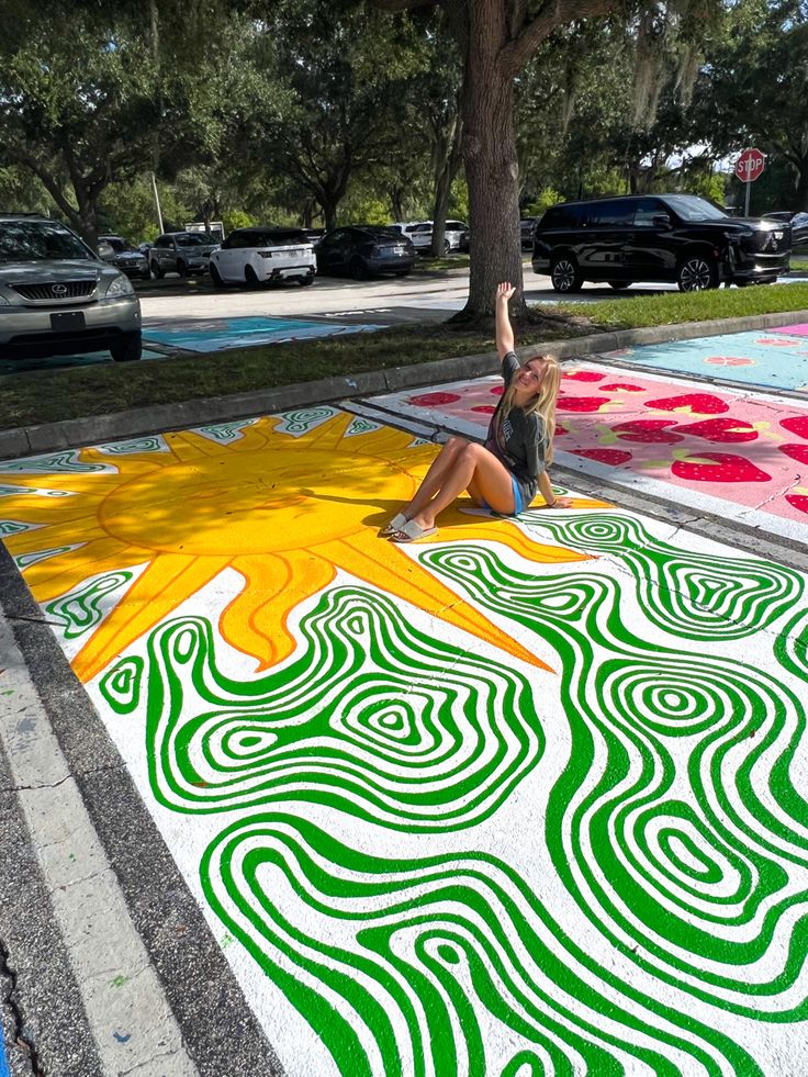 a woman sitting on the ground in front of a chalk art mural that looks like a tree