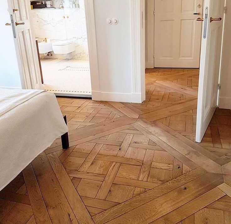 an open door leading into a bedroom with wood floors and white walls on the other side