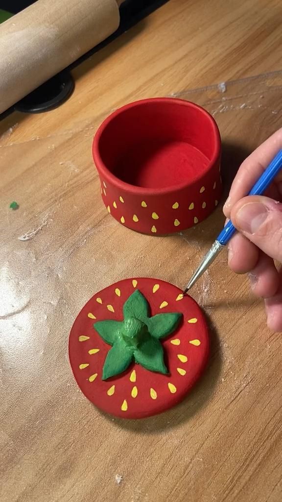 a person is painting a red object with green leaves