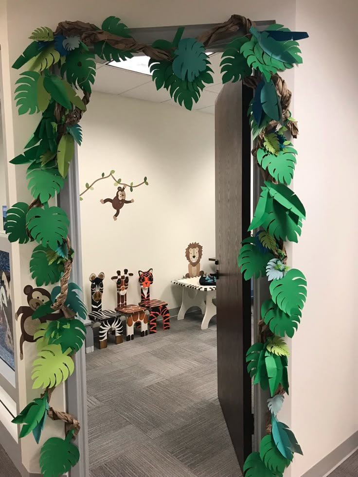 an office hallway decorated with paper jungle animals and leaves on the door frame for decoration