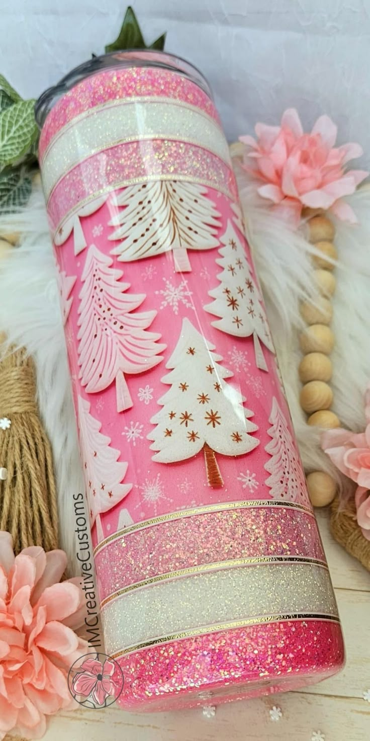 a pink and white christmas tree canister on a table with other items around it