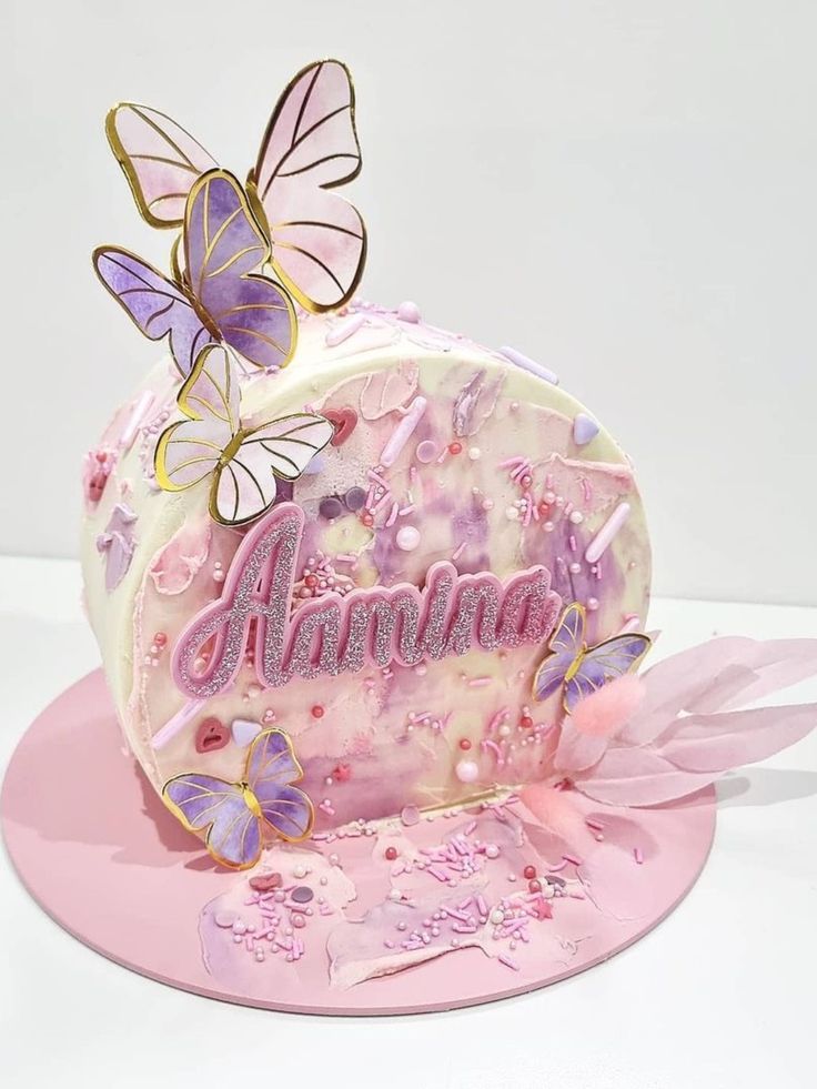 a pink cake with butterflies on it and the word autumn written in white frosting