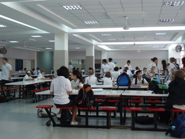 many people are sitting at tables in the cafeteria