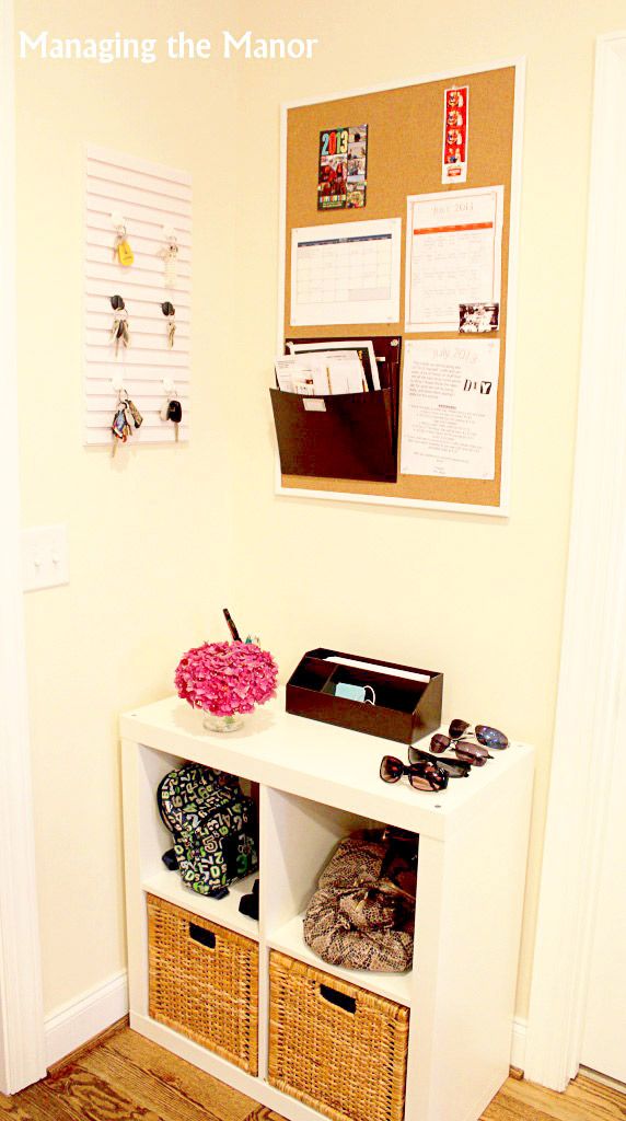 a small white desk with baskets on it and a bulletin board attached to the wall