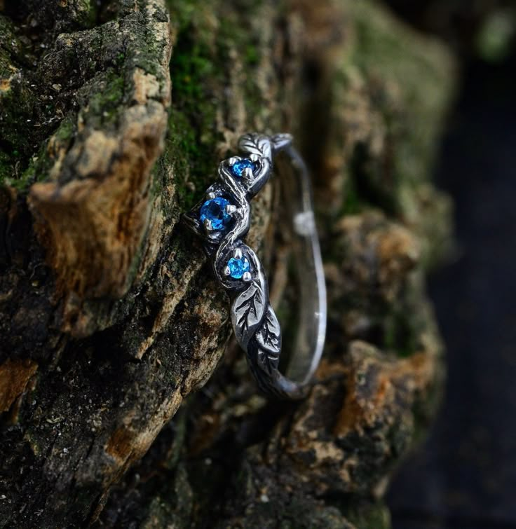 a close up of a ring on a tree branch with blue stones in the background