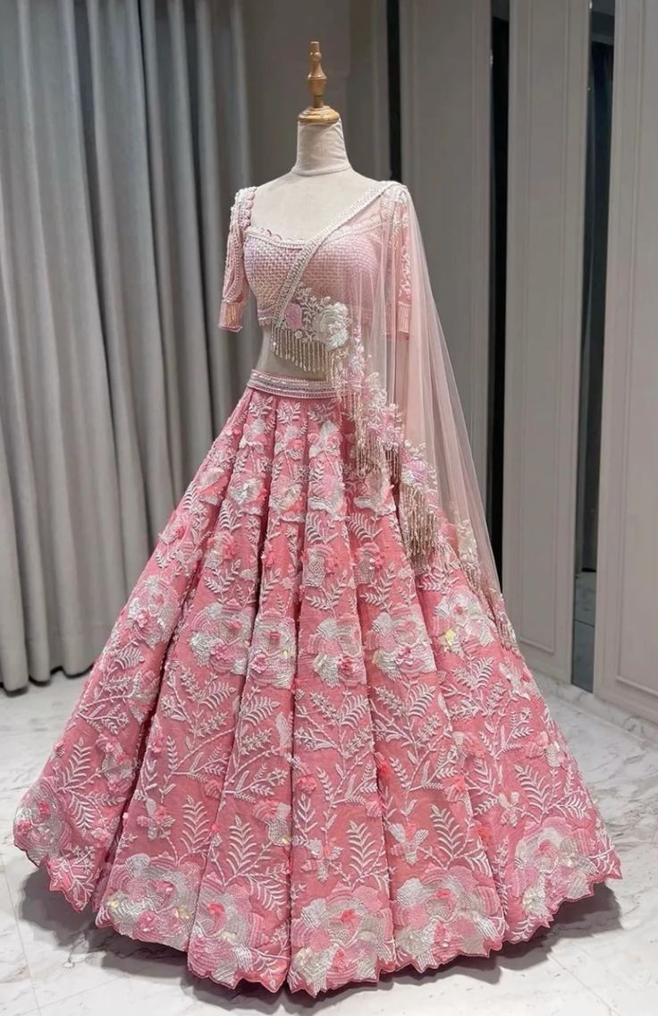 a pink and white gown on display in front of a window with curtains behind it