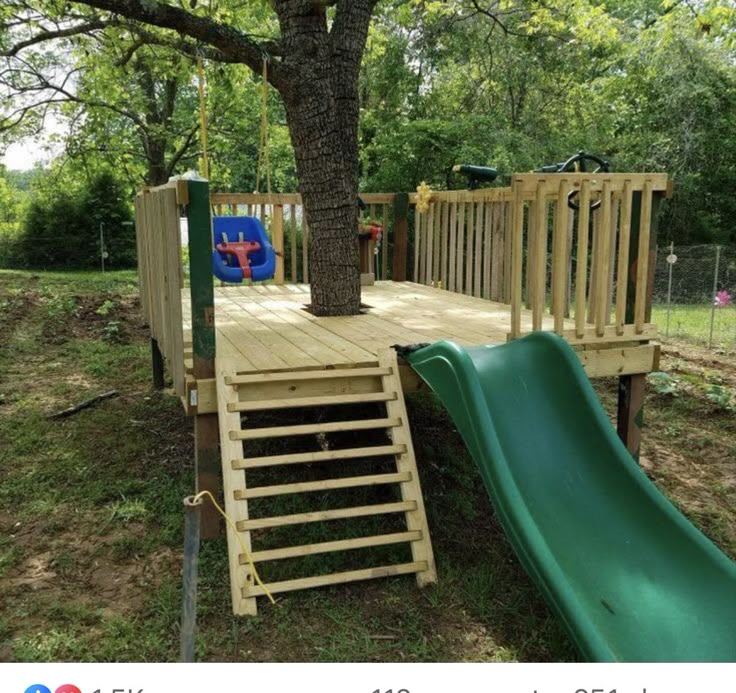 a wooden playground with a slide and tree