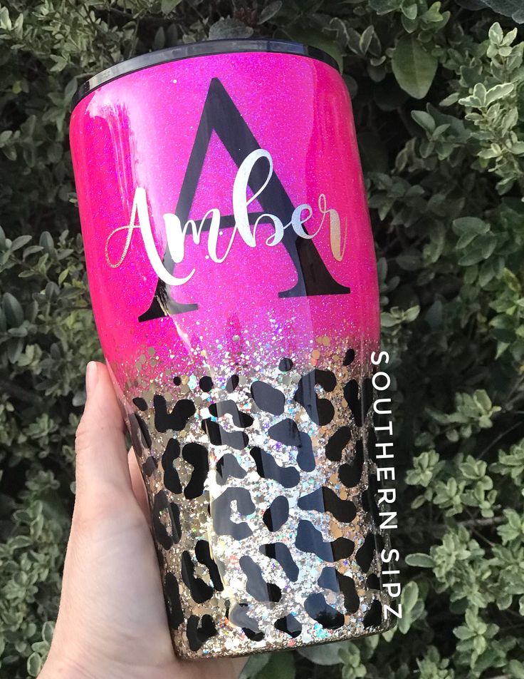 a person holding up a pink and black tumbler with the name amber on it