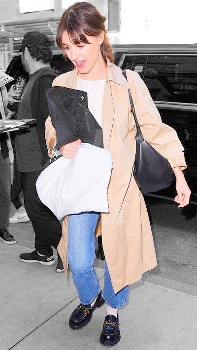 a woman walking down the street carrying a bag and wearing blue jeans with black shoes