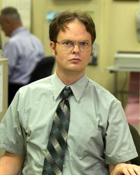 a man wearing glasses and a tie sitting in an office