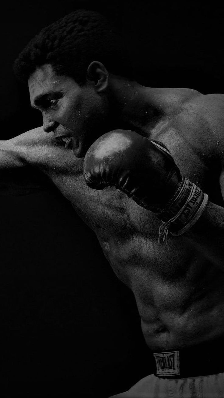 a black and white photo of a shirtless man with boxing gloves on his chest