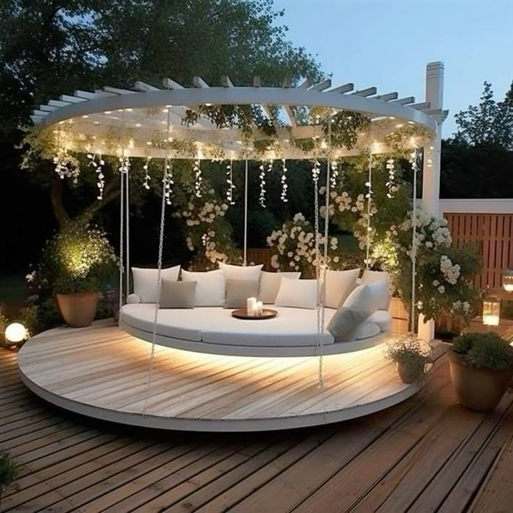 a white couch sitting on top of a wooden deck next to potted plants and lights