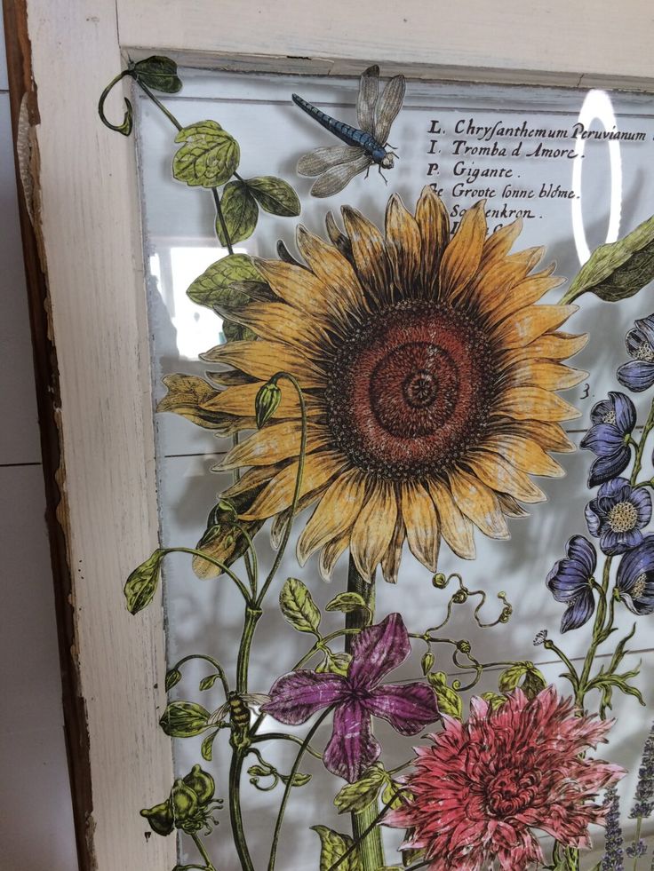 a sunflower and other flowers are on display in a glass frame with butterflies around it