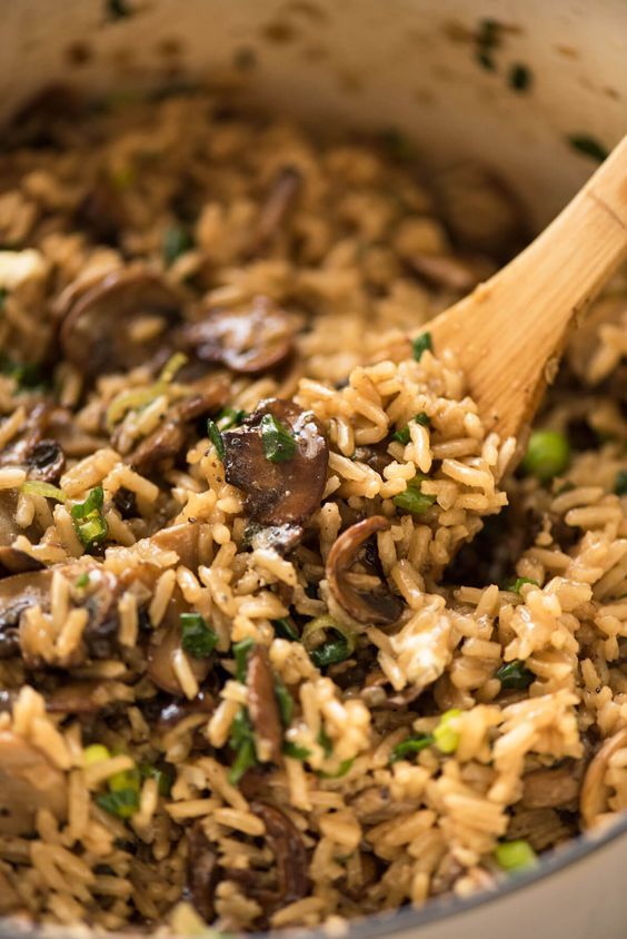 mushrooms and rice in a pot with a wooden spoon