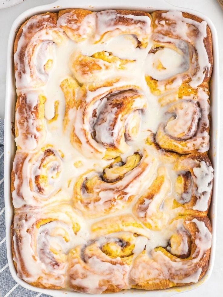 a pan filled with cinnamon rolls covered in icing