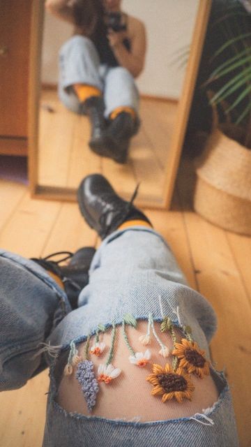 a person with sunflowers on their legs is sitting in front of a mirror