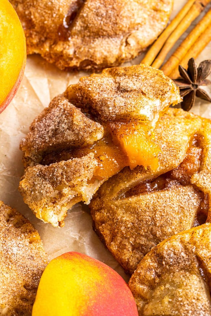 an apple pie with cinnamon sugar on top next to two peaches and some cinnamon sticks