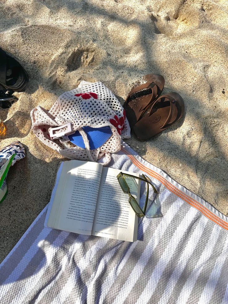 an open book and some shoes on the sand