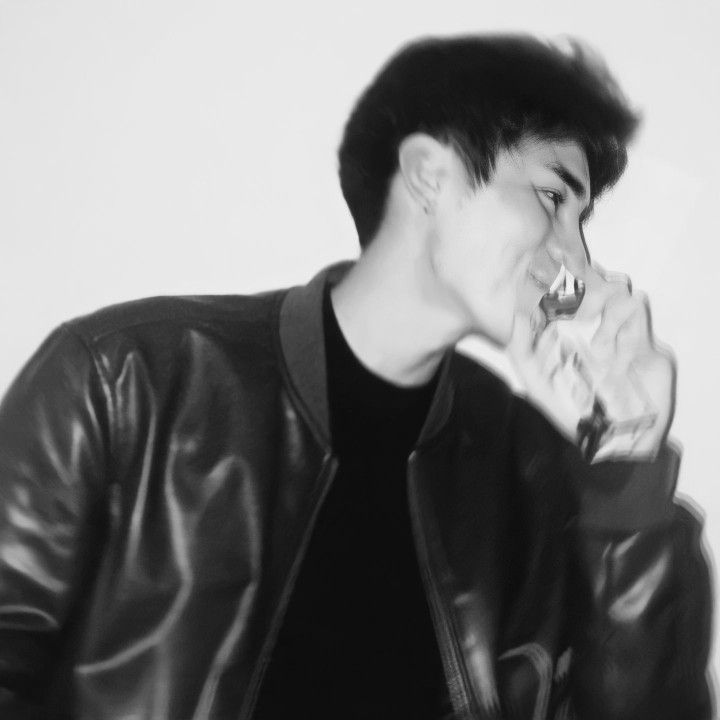 a black and white photo of a man in a leather jacket talking on a cell phone