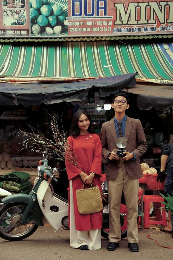 a man and woman standing next to each other in front of a store with green awnings