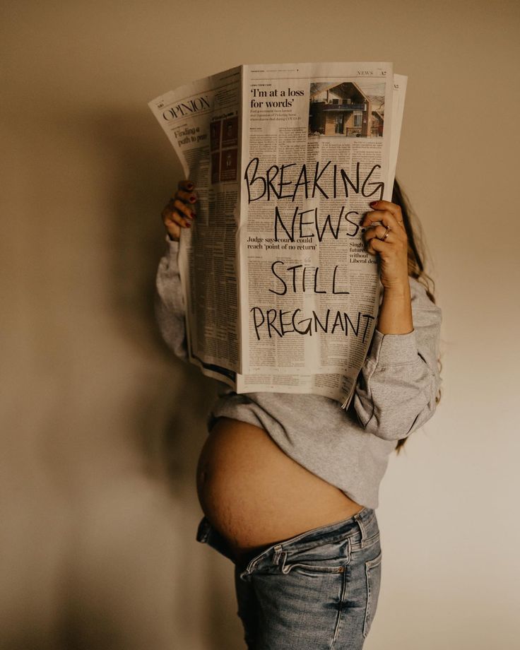 a pregnant woman holding up a newspaper with the words breaking news still pregnant