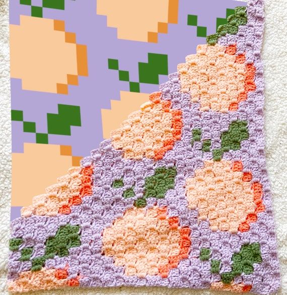 a crocheted blanket with an orange and purple flower design on it's side