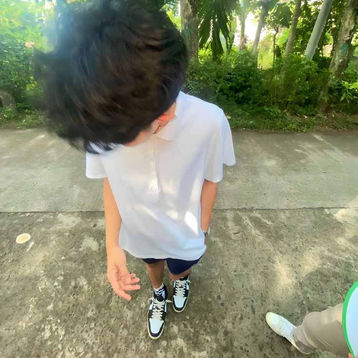 a young boy standing on top of a cement ground next to a person wearing tennis shoes