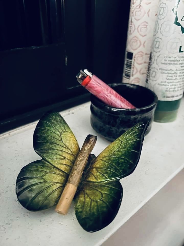 a green leaf shaped candle holder next to a black cup with a pink lipstick in it