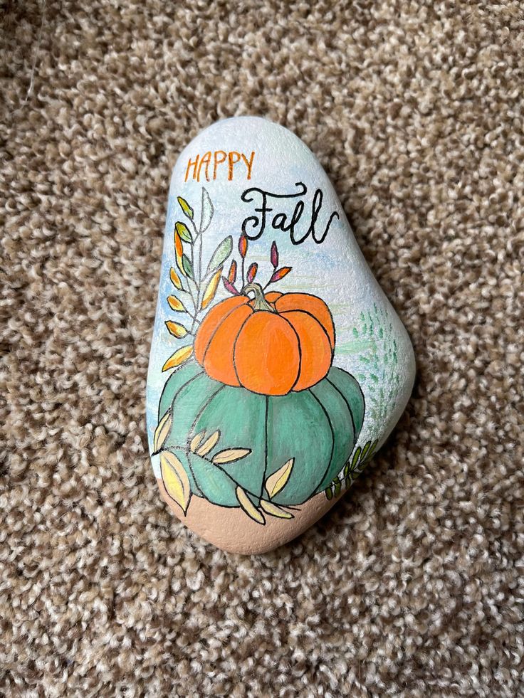 a painted rock that says happy fall on it