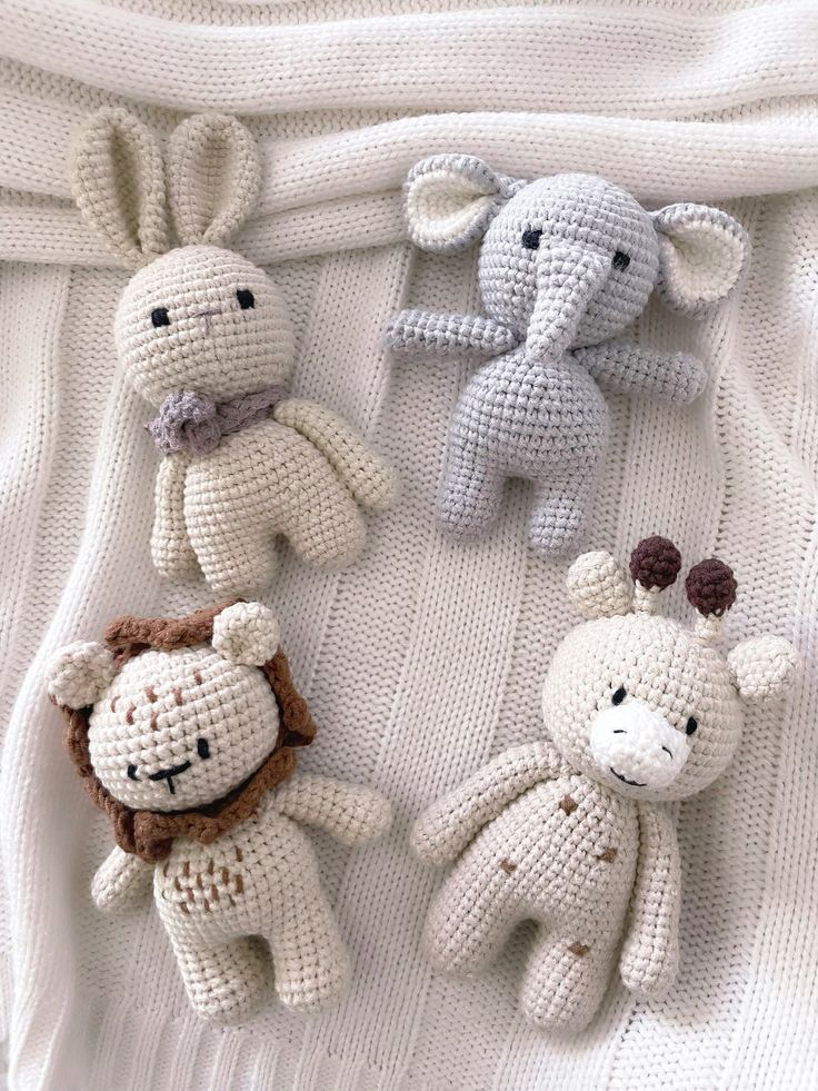 three crocheted stuffed animals sitting on top of a white blanket next to each other