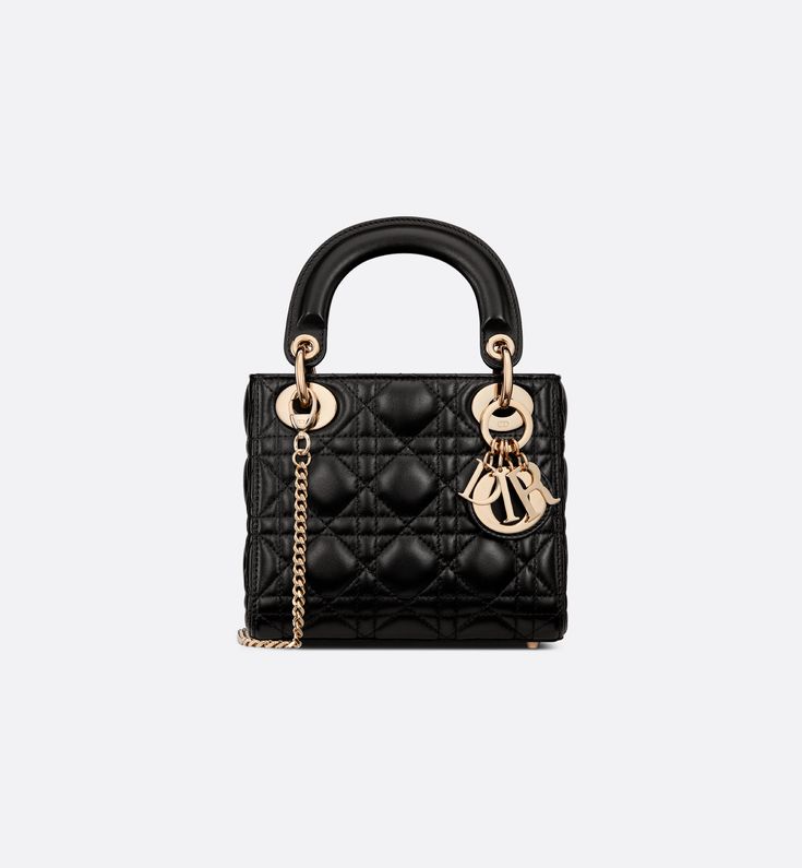 The Lady Dior bag epitomizes the House's vision of elegance and beauty. Refined and sleek, the timeless creation is crafted in black lambskin and covered with Cannage stitching, creating an instantly recognizable quilted texture. The pale gold-finish metal D.I.O.R. charms embellish and illuminate its silhouette. Featuring a removable chain shoulder strap, the miniature Lady Dior bag can be carried by hand or worn crossbody as an ideal evening wear companion.. Lady Dior Bag Outfit, Lady Dior Bag Black, Dior Bag Outfit, Designer Wishlist, Dior Mini Bag, Lady Dior Mini, Dior Purse, Mini Lady Dior, Lady Dior Handbag