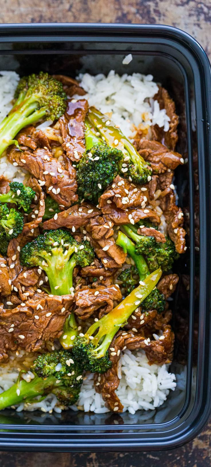 beef and broccoli on rice in a black container