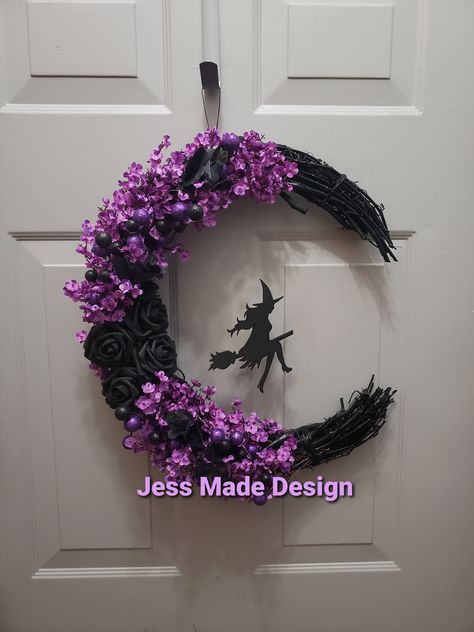 a wreath with purple flowers and a black witch silhouette on it is hanging on the front door