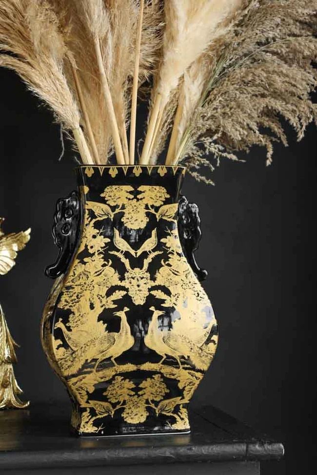 a black and gold vase sitting on top of a table next to a golden statue