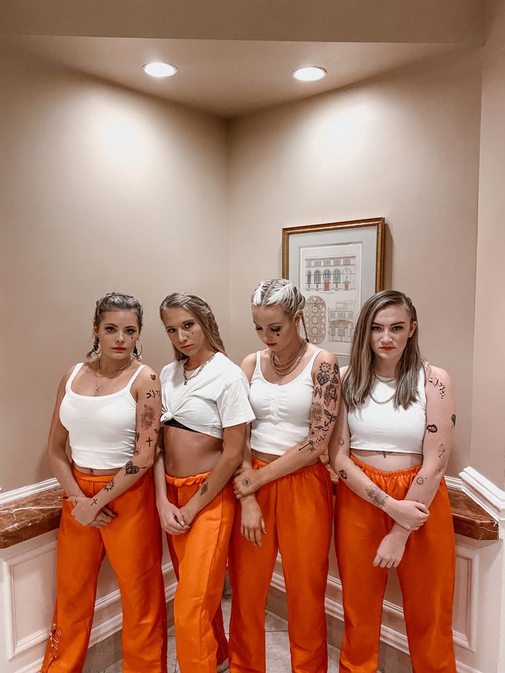 four women in orange pants are posing for the camera