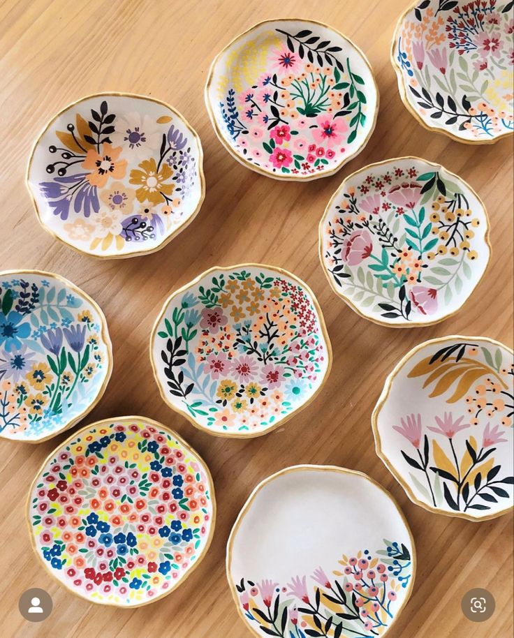 six bowls with painted flowers on them sitting on a wooden table next to each other