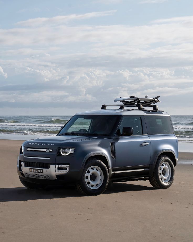 an suv is parked on the beach near the water