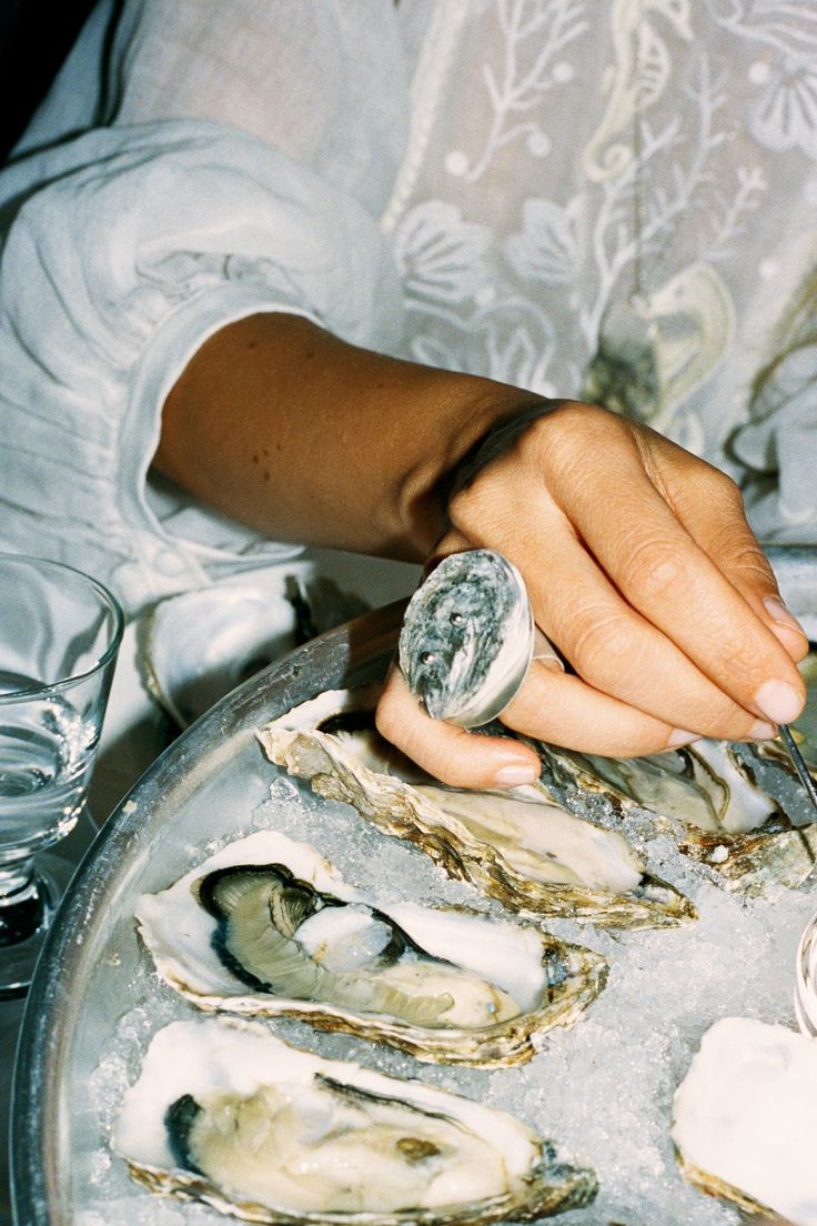 a woman is cutting oysters on a platter