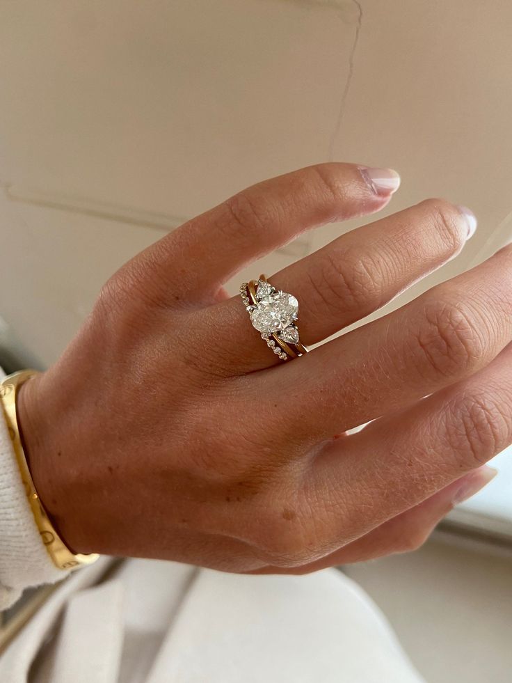 a close up of a person's hand with a diamond ring on their finger