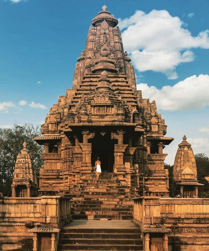 a woman standing in the doorway of an ancient temple with steps leading up to it