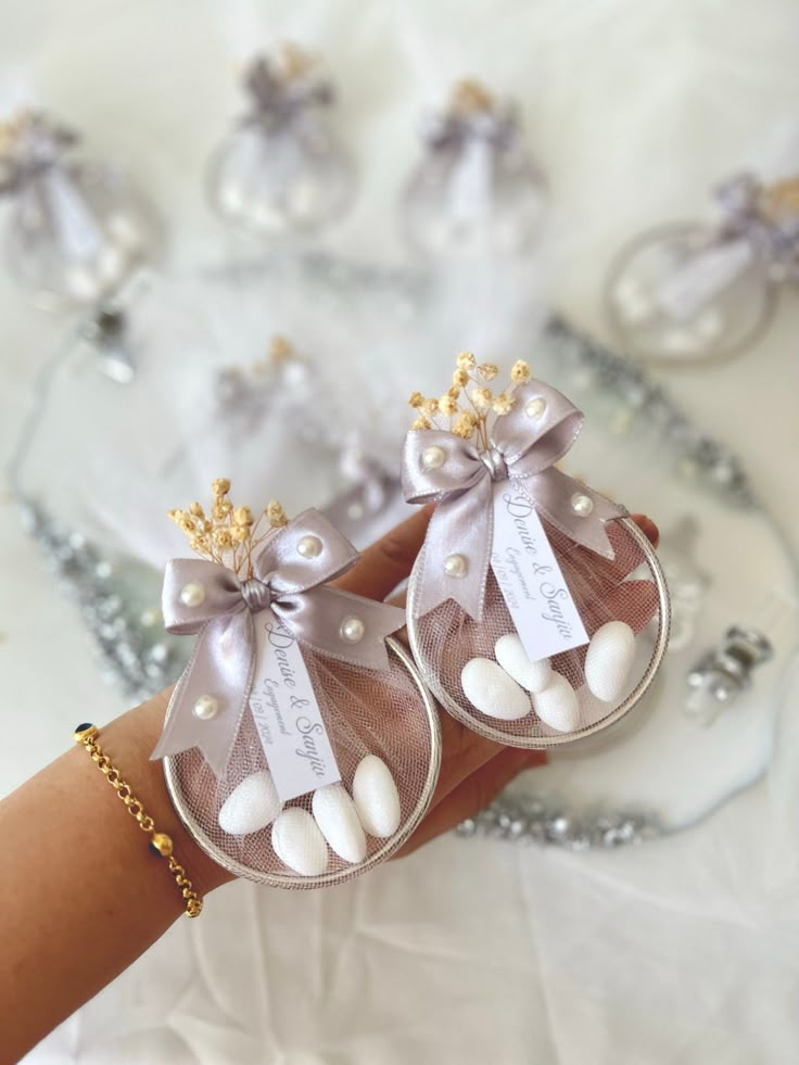 a woman's hand holding two small purses with pearls and bows on them