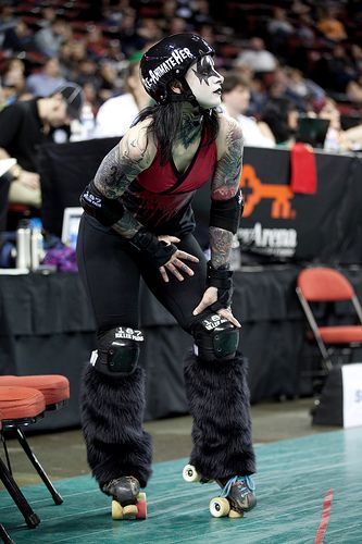 a man in black and red riding on roller skates at a sporting event with other people watching from the bleachers