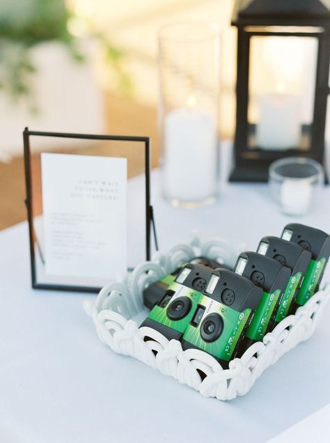 there are four cameras in the tray on the table next to candles and a card